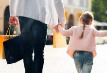 Young child in pink sweater holding her parents h和